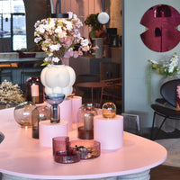 Stylish decor featuring pink, white, and glass vases with floral arrangements and soft pastel hues for a modern aesthetic.