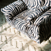 Zebra-striped armchair in black and white, featuring bold patterns and a textured fabric on a light carpet.