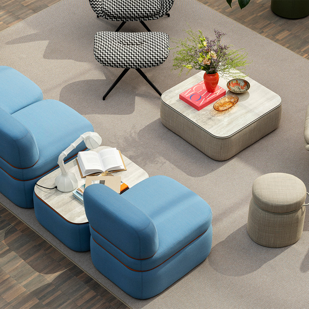 Modern living room featuring blue sofas, black and white zigzag patterned chair, and neutral beige accents.