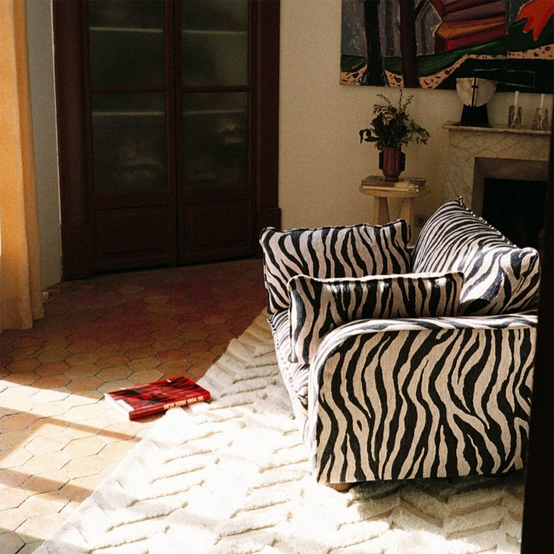 Black and white zebra-striped sofa on a warm-toned hexagonal patterned floor with a light beige rug.