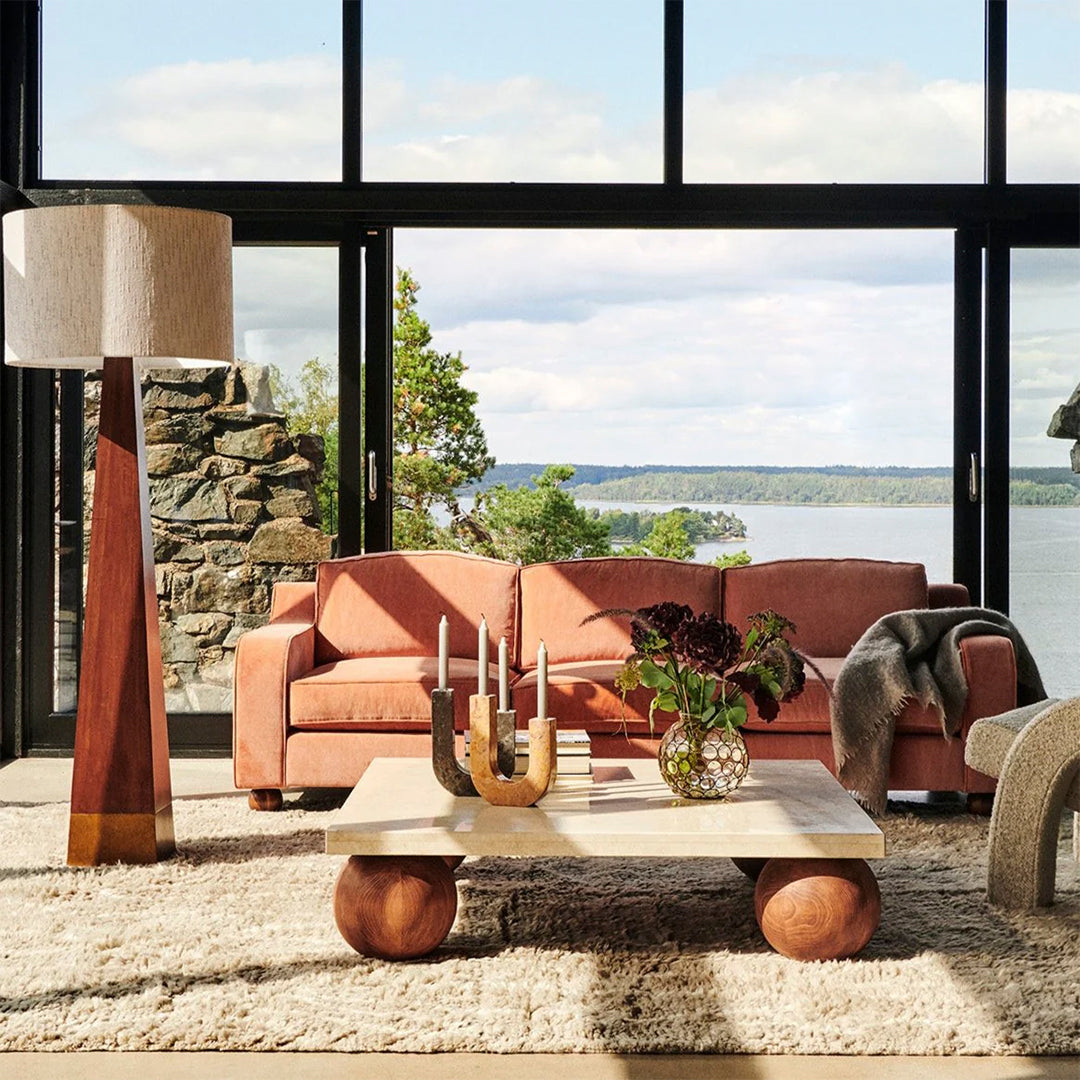 "Soft pink sofa, neutral textures, earthy tones, and geometric patterns complementing a serene natural backdrop."