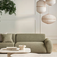 Textured olive green sofa with a soft pattern, complemented by light neutral shades and elegant hanging light fixtures.