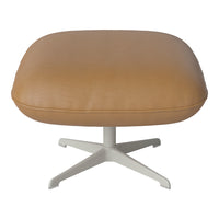 Tan leather ottoman with a textured finish and a sleek white metal base, perfect for modern decor.