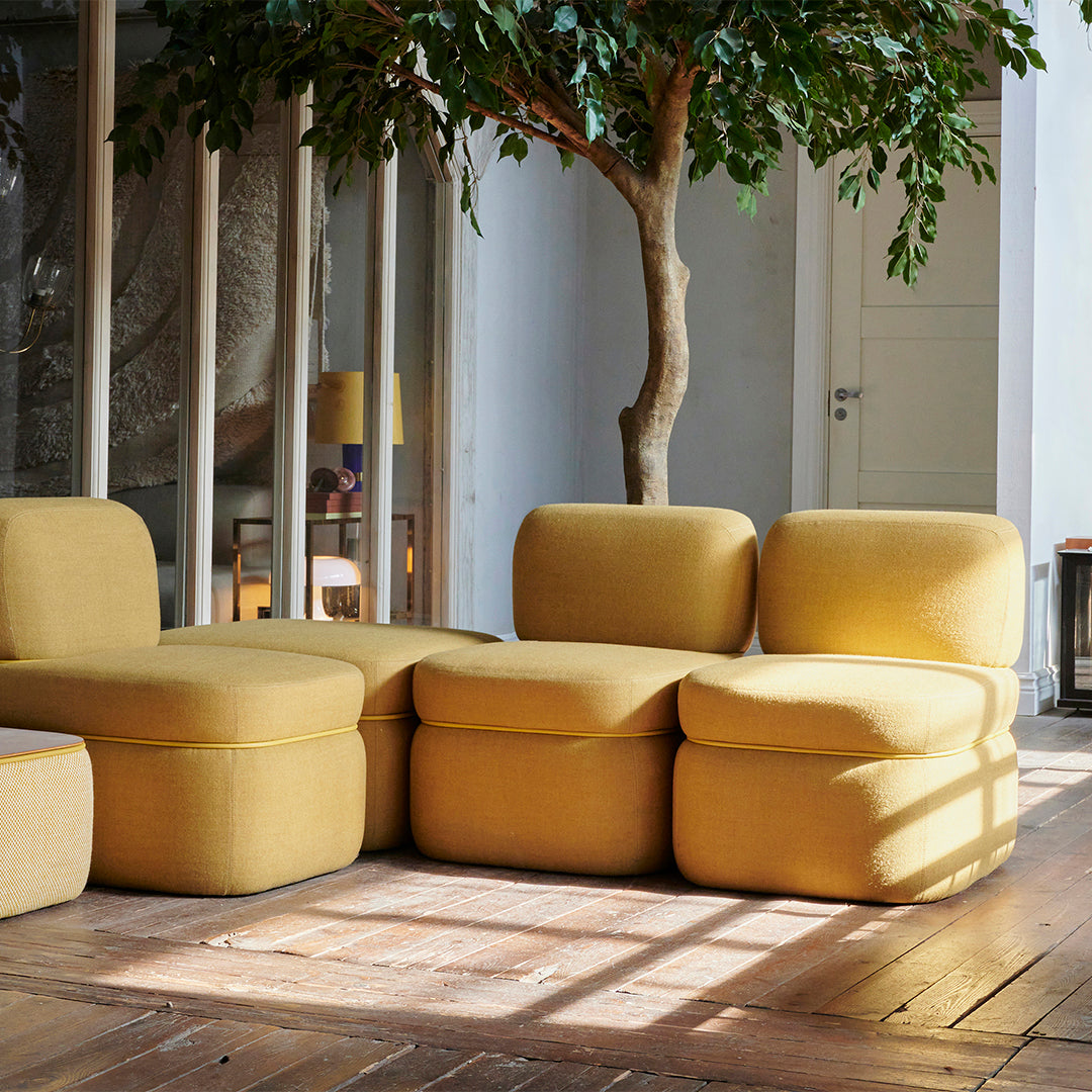 Yellow modular sofa with soft texture and rounded shapes, complementing a warm, natural wood floor.