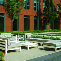 Modern outdoor furniture set featuring gray cushions and green striped accents against a brick backdrop.