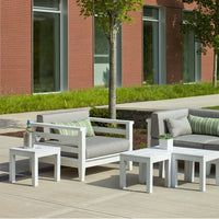 Outdoor furniture set featuring gray cushions with green stripes on a white frame, set against a modern brick background.