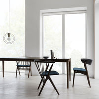 Modern wood dining set featuring dark brown chairs with blue cushions, minimalist design and neutral tones in a bright space.