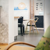 Stylish black and natural wood chairs with a minimalist design in a bright, modern dining space with soft textures.