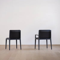 Black modern chairs with sleek design, featuring matte finish and minimalist lines on a light wood floor.