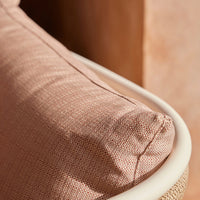 Soft pink cushion with subtle texture, complemented by a smooth white frame and warm neutral backdrop.
