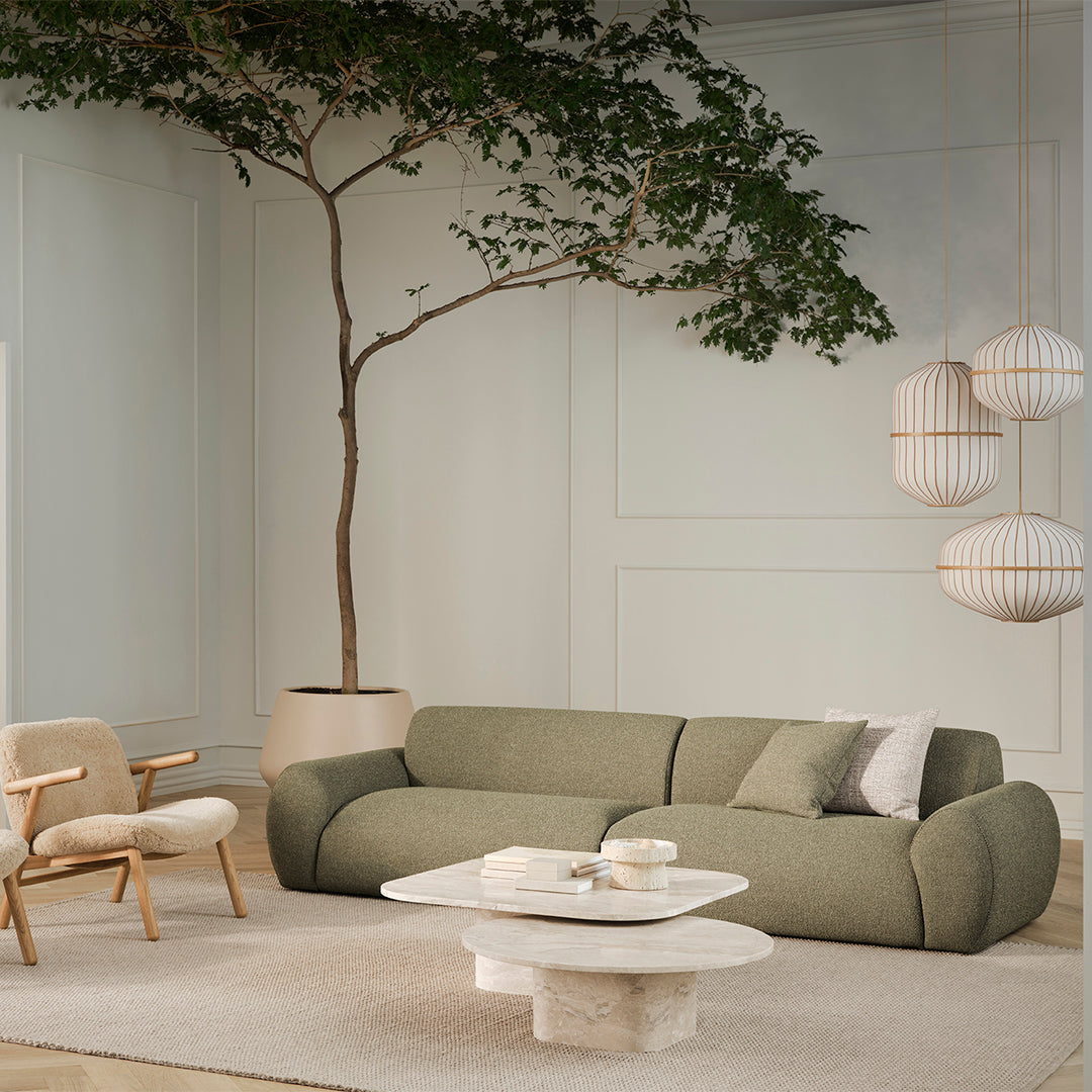 Modern olive green sofa with light gray cushion, paired with textured beige rug and neutral coffee table in a stylish setting.