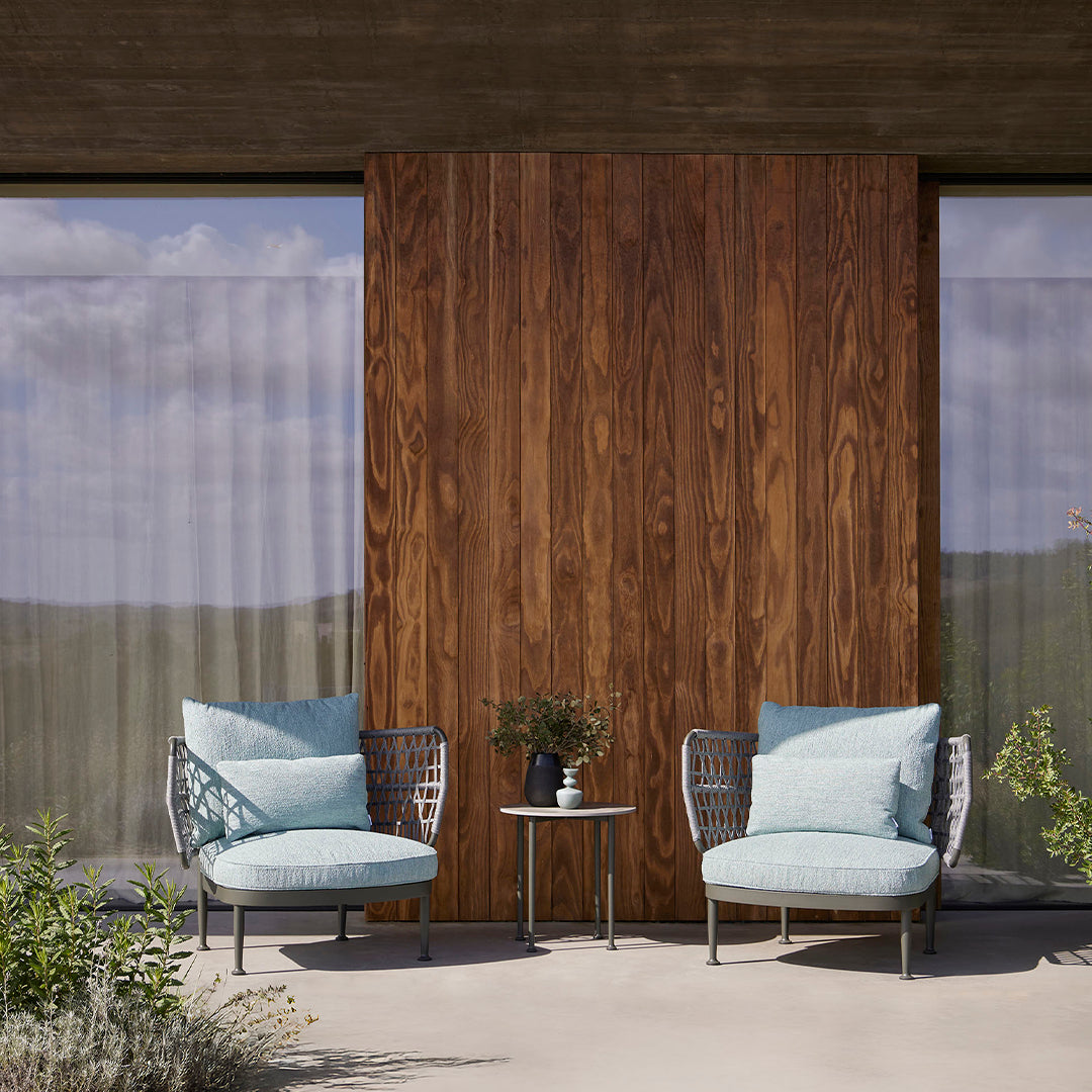 Light blue cushions on modern chairs, set against rich wood paneling and soft, neutral surroundings.