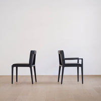 Black upholstered chairs with sleek, minimalist design against a light, neutral background.