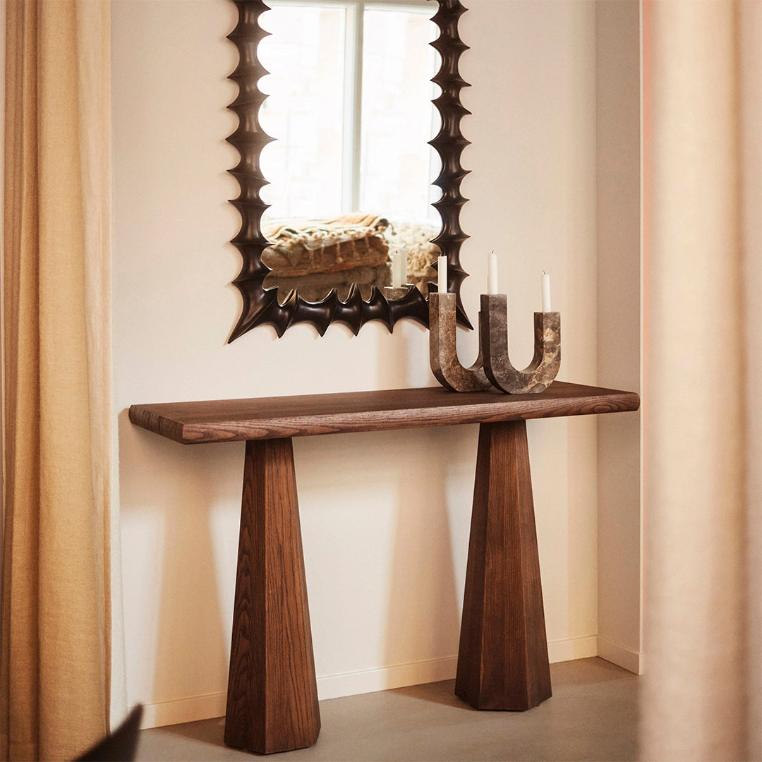 Wooden console table in rich brown with a textured dark mirror and soft beige curtains. Simple yet elegant design.