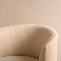 Beige textured fabric sofa arm against a soft beige background, creating a minimalist aesthetic.