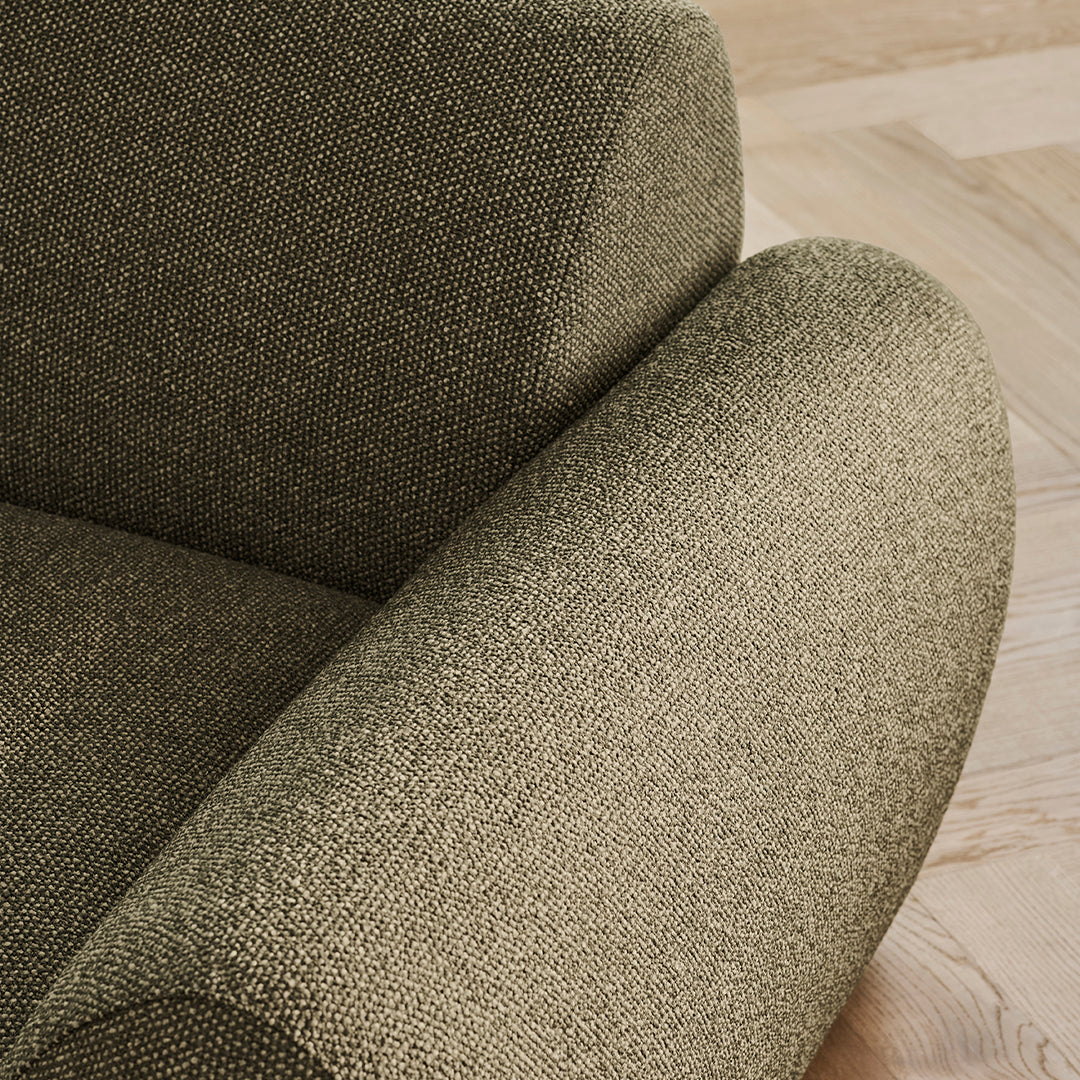 Textured olive green upholstery on rounded chair arm, showcasing a subtle, woven pattern.