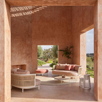 Modern living room featuring warm terracotta walls, soft beige furniture, and muted coral accents in a serene outdoor setting.