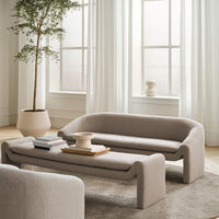 Soft beige sofa and coffee table against a light, airy backdrop with warm white curtains and natural wood accents.