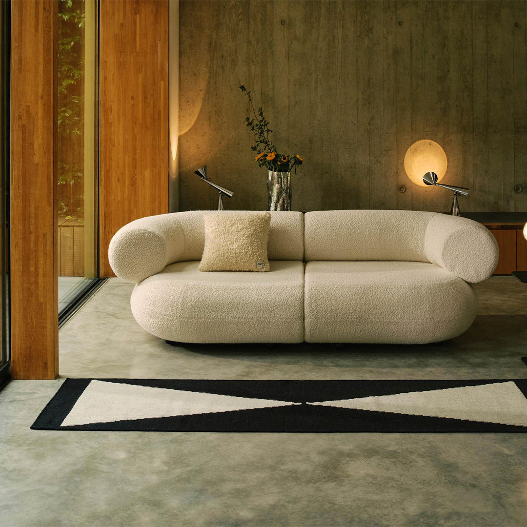 Cream-colored sofa with textured fabric, paired with a black and cream geometric rug in a modern living space.