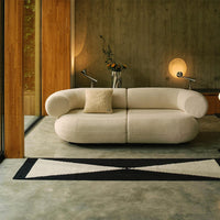 Cream-colored sofa with textured fabric, paired with a black and cream geometric rug in a modern living space.