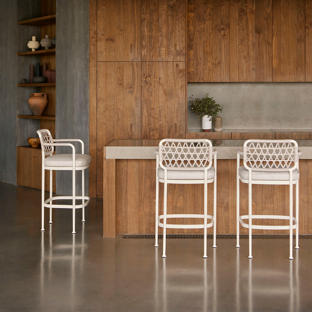 White woven bar stools against a warm wood backdrop, featuring earthy tones and a smooth, minimalist design.