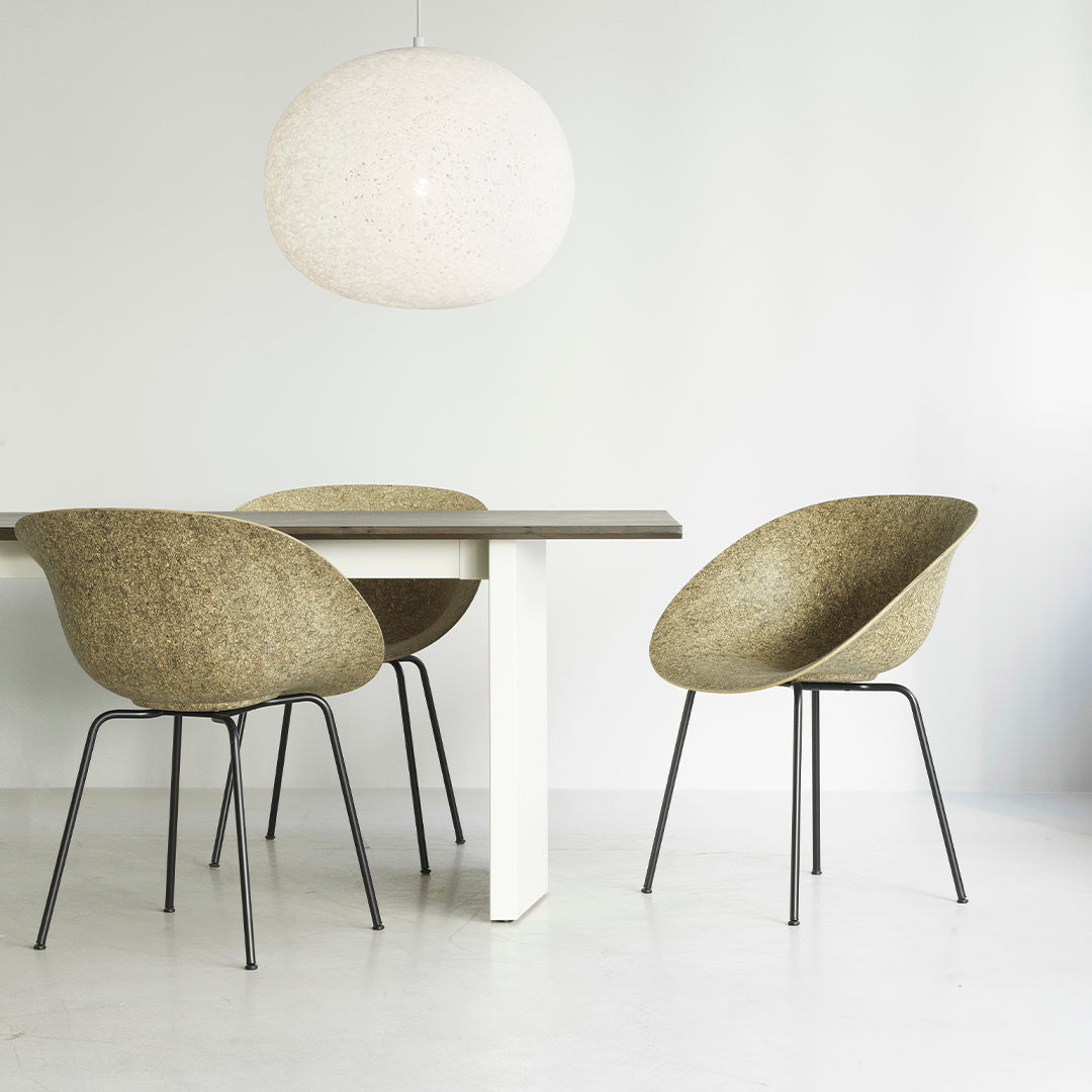 Olive green patterned chairs with sleek black legs around a modern white dining table in a minimalist setting.