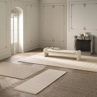 Neutral beige and cream area rugs with soft textures in an elegant, minimalist room setting.