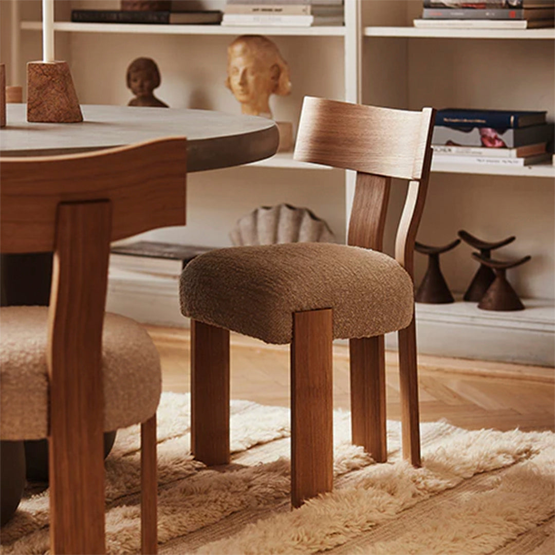 Brown upholstered chair with wooden legs, featuring a soft texture and warm, neutral tones against a cozy background.
