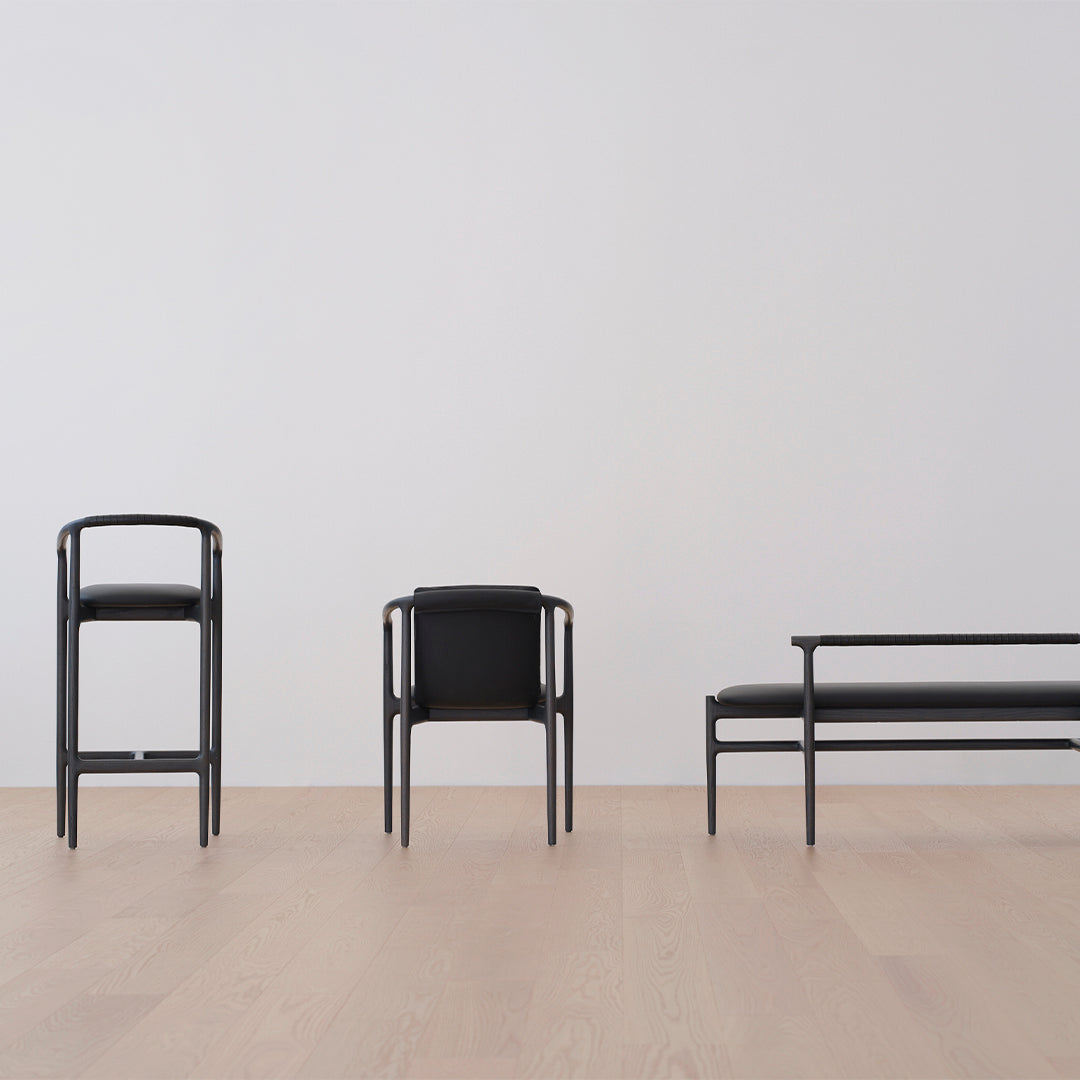 Black modern furniture set against a light wood floor and plain white wall, showcasing sleek lines and minimalistic design.