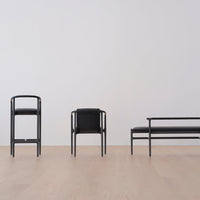 Black modern furniture set against a light wood floor and plain white wall, showcasing sleek lines and minimalistic design.