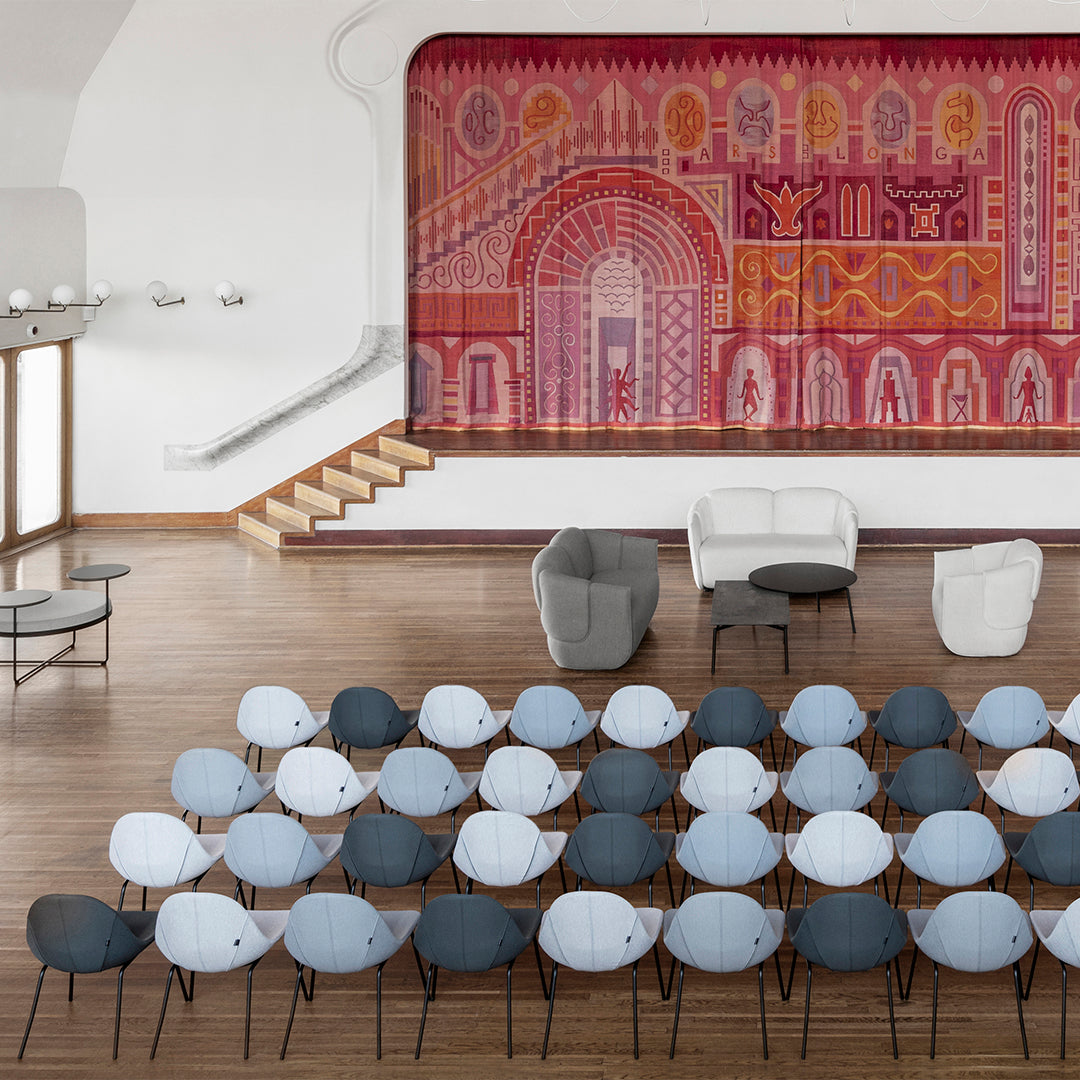 Colorful patterned mural in shades of pink, red, and gold, complemented by gray and blue seating with black legs.