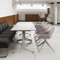 Gray upholstered sofa, light wood table, soft pink chairs, and natural wood accents in a modern minimalist setting.