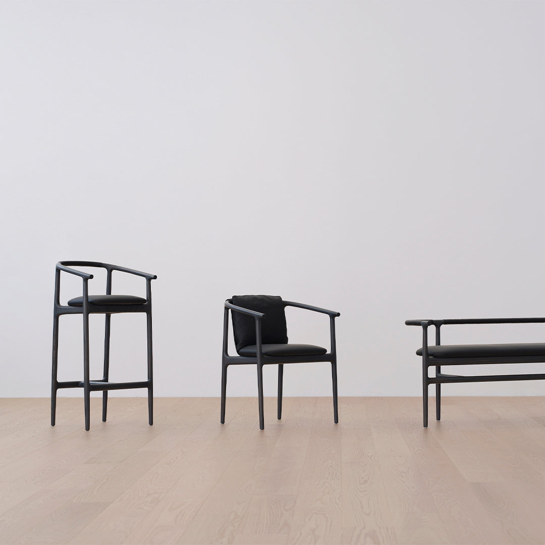 Black wooden chairs with minimalist design, featuring sleek lines and matte finishes, on a light wood floor.