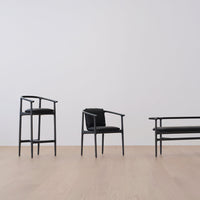 Black wooden chairs with minimalist design, featuring sleek lines and matte finishes, on a light wood floor.