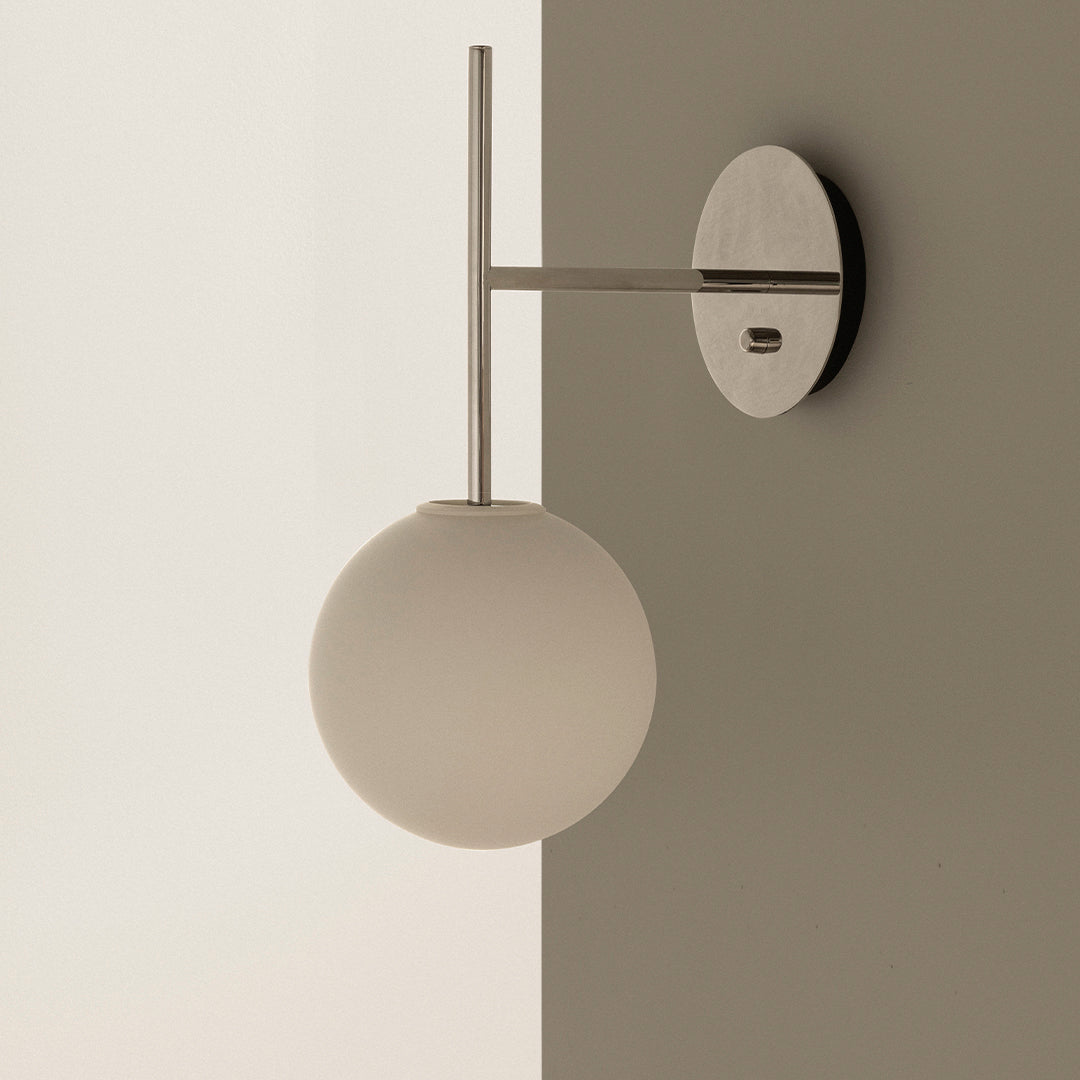 Modern wall sconce featuring a frosted white globe and sleek metallic accents against a neutral background.