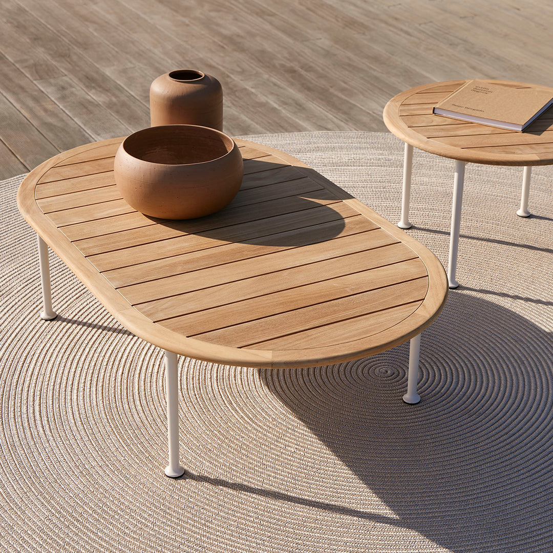 Light wooden coffee table with slatted surface, complemented by round brown pottery on a textured beige rug.