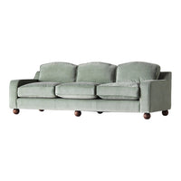 Sofa in soft sage green fabric with rounded cushions and dark wooden feet, offering a contemporary, cozy look.