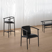 Black upholstered chairs with sleek, curved frames and a minimalist design, placed on light wooden flooring.