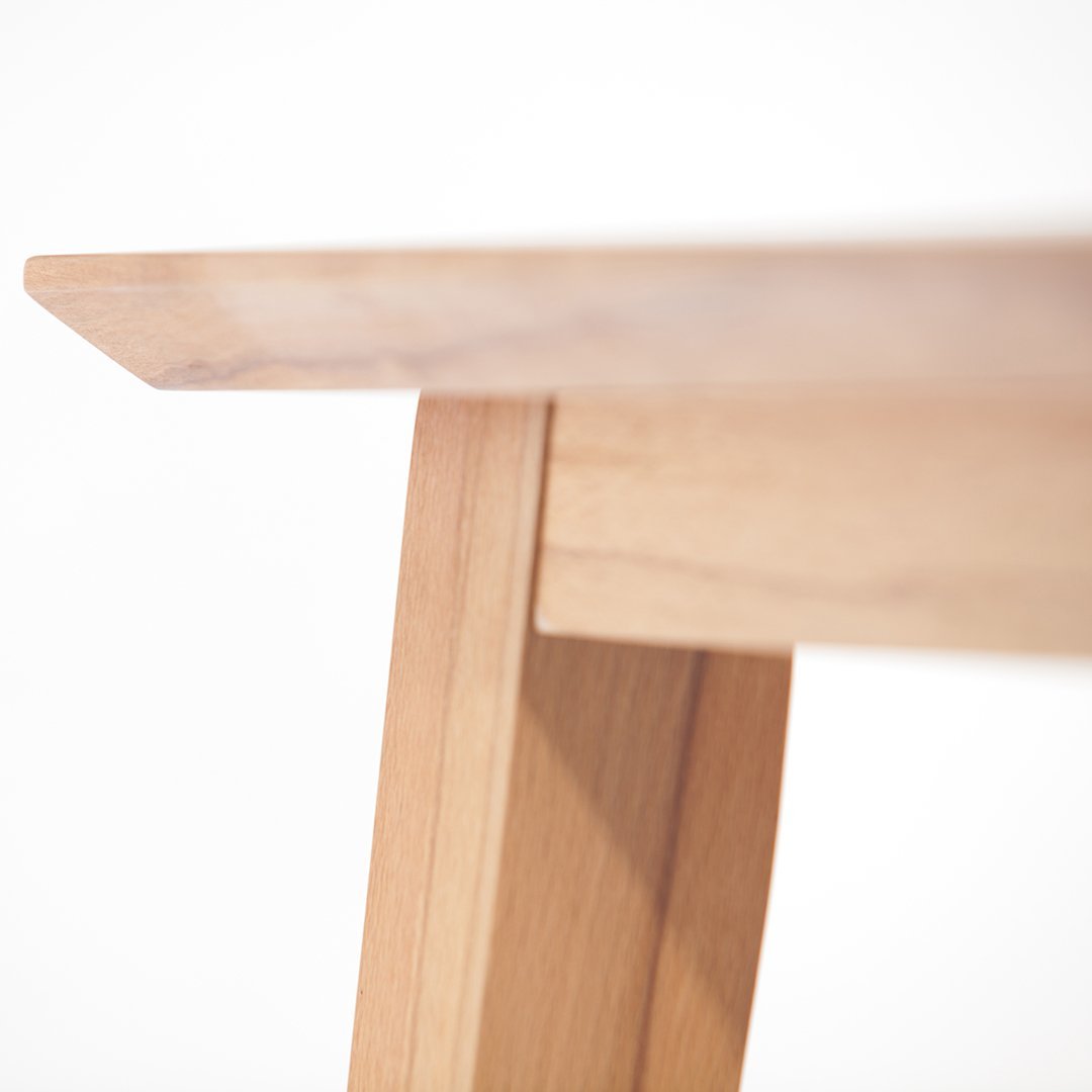 Natural light wood table with a smooth finish and minimalist design, showcasing clean lines and subtle grain patterns.