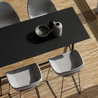 Black table with gray chairs and wooden flooring, featuring minimalist ceramics in neutral tones.
