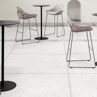 Light gray bar stools with black metal legs on a white terrazzo floor, featuring soft textured upholstery.