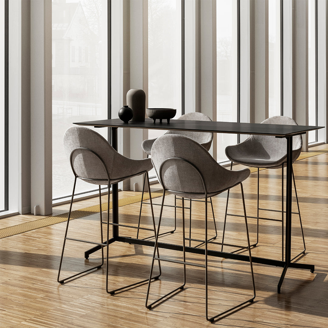 Gray upholstered bar stools and black table on a warm wooden floor, enhancing a modern and minimalist aesthetic.