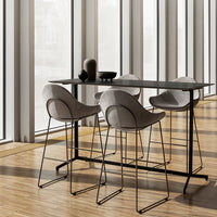 Gray upholstered bar stools and black table on a warm wooden floor, enhancing a modern and minimalist aesthetic.