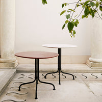 Two round tables in deep red and crisp white with black metal bases, set against a simple, elegant backdrop.