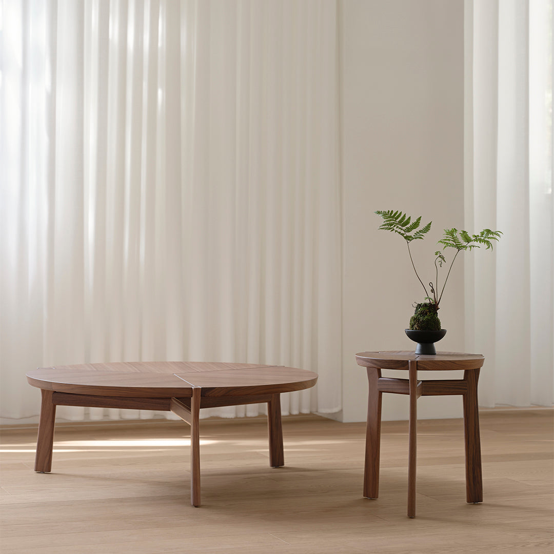 Wooden coffee tables in warm walnut tones with sleek designs, set against soft white curtains.