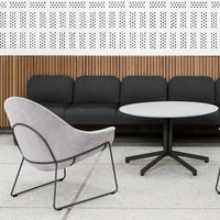 Gray velvet chair and charcoal sofa against a wood-panelled wall, complemented by a round white marble table.