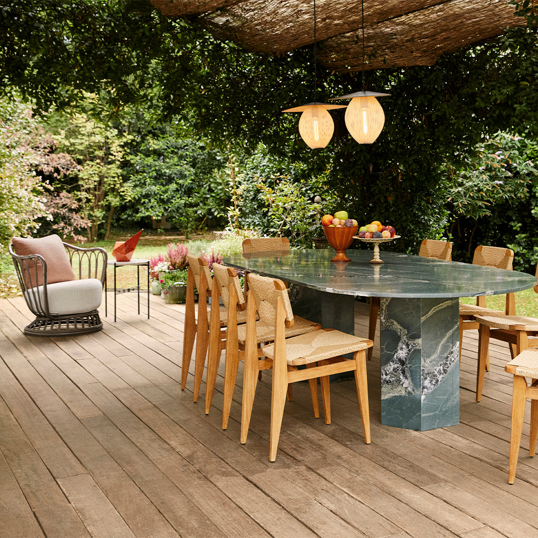 "Outdoor dining set featuring earthy tones, green marble table, natural wood chairs, and soft neutrals in decor."