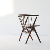 Mid-century modern chair in rich walnut wood with a light gray cushion and geometric spindle back design.