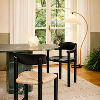 Black chairs with woven seats beside a green marble table, against earthy tones and soft neutral patterns.