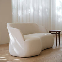 Light beige sofa with a smooth, minimalist texture and soft, contoured shape, complementing a neutral decor.
